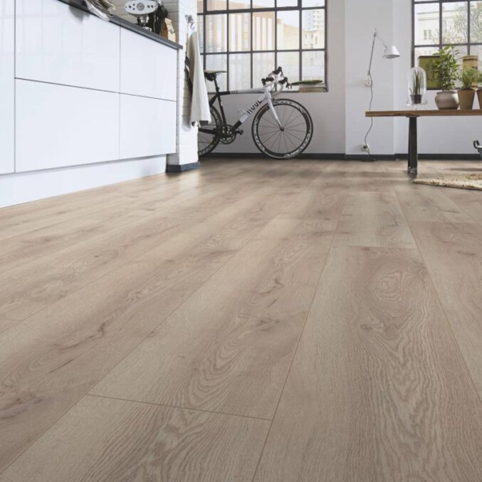 Raumfoto eines Laminats in einem großen Mehrzweckraum. Das Laminat hat eine Holzoptik mit leichten Furchen und ist gefärbt in einem hellen Beige.