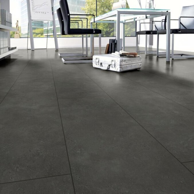 Raumfoto eines Laminats in einem Büro. Das Laminat hat eine schwarze Steinfliesenoptik und extra breite Dielen.