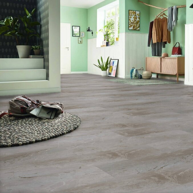 Raumfoto eines Laminats in einem großen Eingangsbereich. Das Laminat hat eine graue und braune Marmoroptik und besonders breite Dielen.