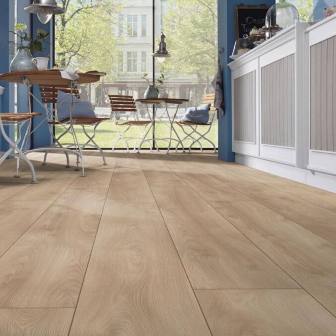 Raumfoto eines Laminats in einer Küche. Das Laminat hat eine Eichenholzoptik in beiger Farbe und feiner Holzmaserung und besonders lange Dielen.