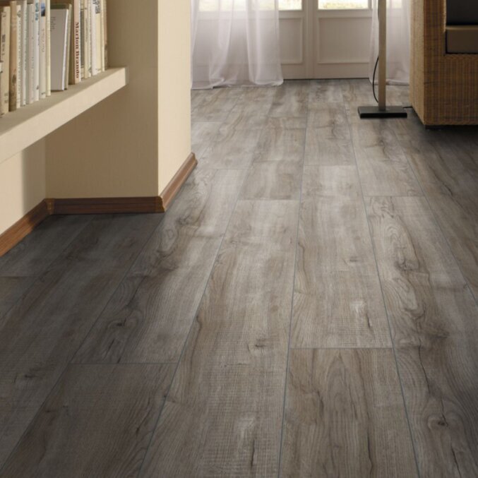 Raumfoto eines Laminats in einem Wohnraum. Das Laminat hat eine rustikale Eichenholzoptik mit dunklen Rissen und breite Dielen. Gefärbt in einem silbrigen dunkelgrauen Farbton.