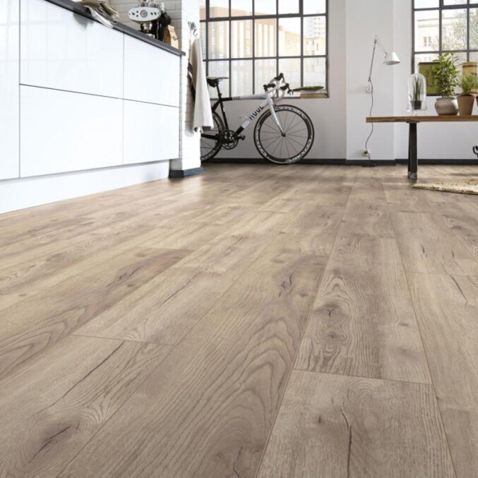 Raumfoto eines Laminats in hellbeiger Eichenholzoptik in einer Küche mit schwarzen Rissen.