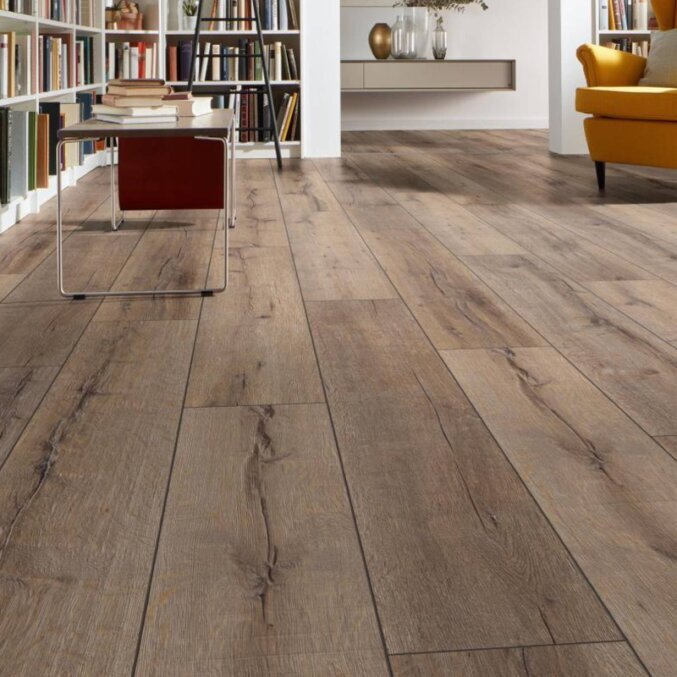 Raumfoto eines Laminats in einem Leseraum. Das Laminat hat eine rustikale Eichenholzoptik mit schwarzen und langen Rissen sowie breite Dielen. Gefärbt in einer Mischung aus Grau und Braun.