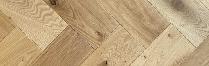 Nahaufnahme des Fischgrät Parkett aus Eichenholz. In brauner Farbe mit leichten Holzmaserungen.