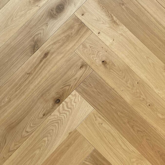 Flächenaufnahme eines Fischgrät Parkett aus Eichenholz. In brauner Farbe mit leichten Holzmaserungen.